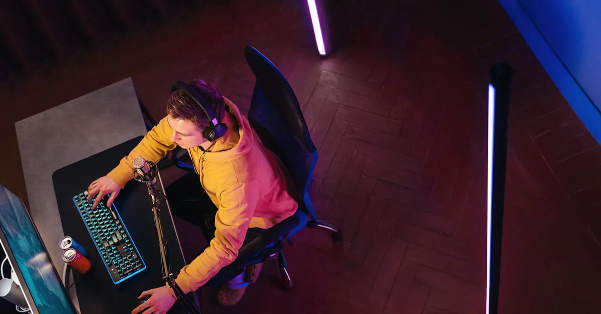 Joven gamer jugando videojuegos en una computadora de escritorio con audífonos y setup de luces