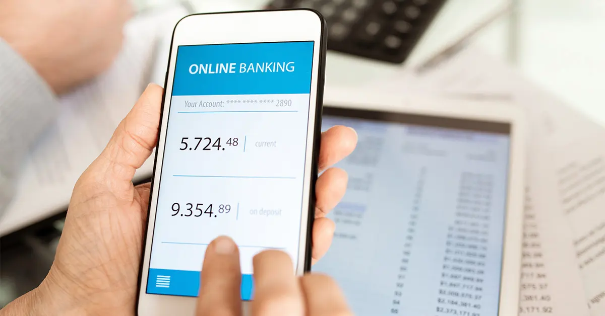 Persona realizando trámites por internet en su smartphone para consultar saldo de cuenta.